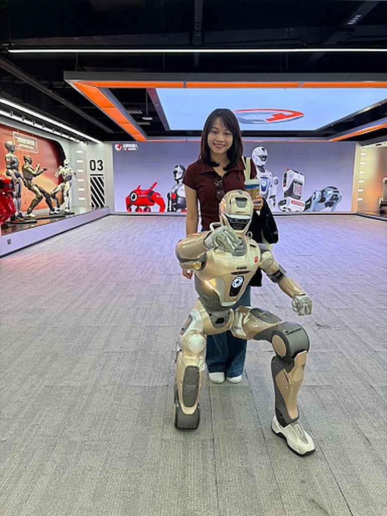 A GenAI Fund team member beside a humanoid robot at a robotics experience centre